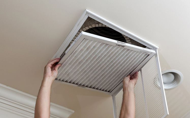 Man opening air conditioning filter in ceiling